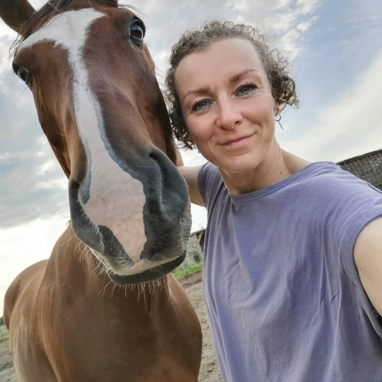 Tierkommunikation Frau posiert lächelnd mit einem braunen Pferd